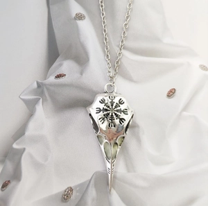 Macro shot of silver viking crow skull pendant with detailed geometric engraving