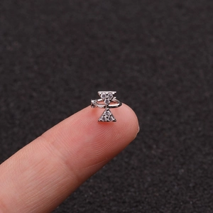 Macro shot of silver cartilage earring with crystal bow design on fingertips