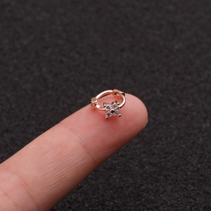 Close-up of mini rose gold flower cartilage earring with cubic zirconia on a fingertip