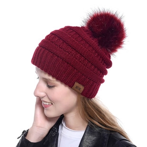 Detail of chunky knit wine red beanie with faux fur pompom and brown leather MOK label