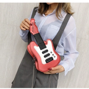 Detailed view of creative red guitar shaped crossbody bag with metal chain strap on model