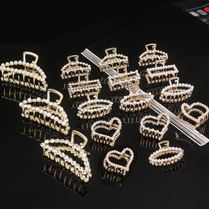 Golden hair claw clips set with elegant pearls and rhinestones on reflective black base