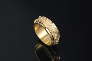 Detailed macro view of golden rotating spinner ring with embossed dragon pattern