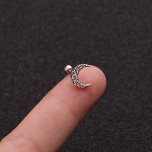 Delicate silver moon stud earrings with zircon inlay held on fingertip for size