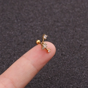 Detailed view of a gold celestial cartilage stud with clear zircons held on a finger