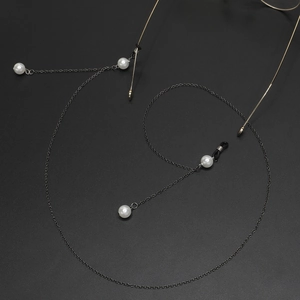 Detailed view of a gold glasses chain featuring elegant white pearls on a dark background