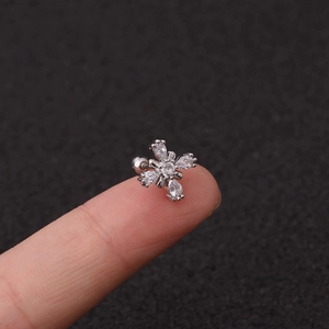 Macro shot of a tiny silver zircon flower stud earring held on a fingertip for scale