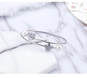 Detail of silver stainless steel wire bracelet with heart, angel charm and white pearls