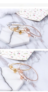 Detailed close-up of woven stainless steel bracelets with pearl heart and butterfly charms