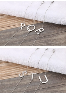 Dettaglio di collane in acciaio inossidabile argento con ciondoli lettere P, Q, R, S, T, U