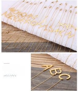 Close-up of gold stainless steel initial pendant necklaces A-Z on plush white background