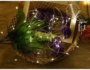 Close-up of warm white LED copper wire lights wrapped on decorative flowers and basket