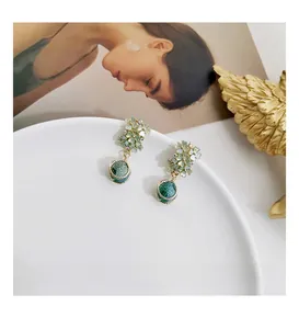 Detailed shot of green floral drop earrings with marble-textured pendants and gold finish