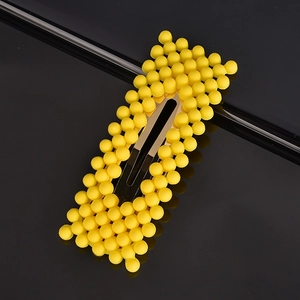 Detail shot of yellow bubble texture hair clip with golden metal base on dark surface