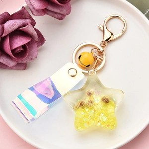 Detail of star-shaped liquid keychain with glitter, dried flowers and golden ring