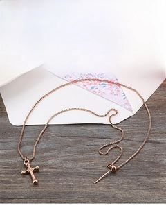 Detail view of rose gold titanium steel cross pendant necklace on wooden background