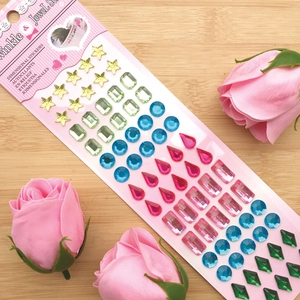 Macro view of colorful multi-shape dimensional crystal gemstone stickers on a pink card