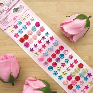 Detailed view of colorful 3D crystal jewel stickers with hearts and stars on wood
