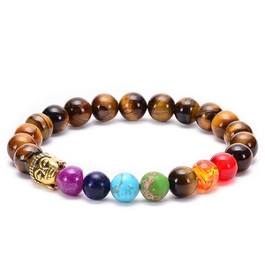 Macro shot of colorful natural stones and golden Buddha head on beaded tiger eye bracelet