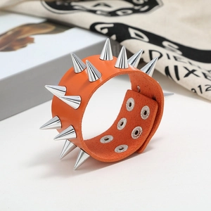 Close-up of orange leather punk bracelet featuring silver metal spikes and snap closure