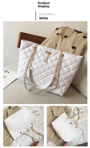 Detail of white quilted tote bag with golden chain strap and deer metal pendant charm
