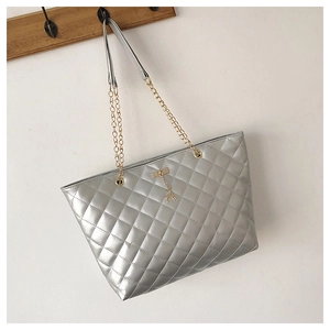 Detail of silver quilted tote bag with gold chain strap and deer pendant ornament