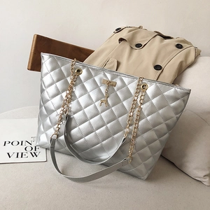 Silver quilted tote bag with golden chain strap and deer charm on a stylish background
