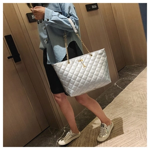 Close-up of silver quilted tote bag with metallic leather and golden chain strap detail