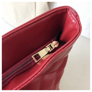 Detailed macro view of red quilted leather texture and premium gold metal zipper pull