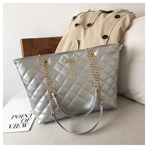 Close-up of silver quilted tote bag with gold deer charm and chain strap details