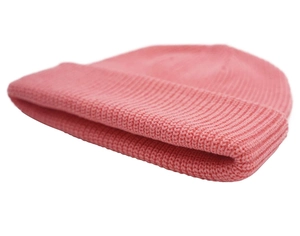 Close-up of pink rib-knitted beanie showing textured fabric and wide cuff detail