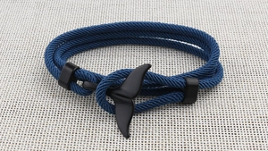 Detail of the dark blue braided cord bracelet featuring a matte black whale tail clasp