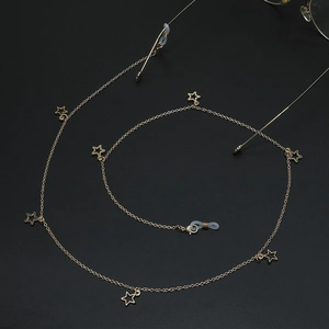 Golden punk star eyewear chain with hollow star charms on a black spiral background