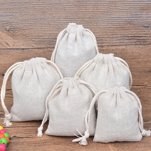 Set of five beige linen cotton drawstring pouches in various sizes on a wooden background