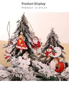 Détail de suspensions de Noël en bois peint à la main sur un sapin de Noël enneigé