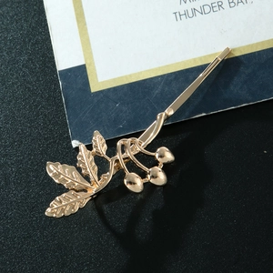 Fermaglio per capelli a fiori con foglie dorate e bacche su sfondo scuro