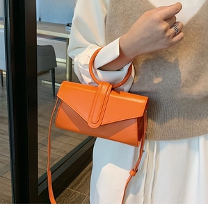 Dettaglio di una borsa arancione vivace con un manico circolare unico e tracolla