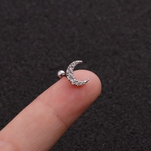 Macro di orecchino a luna in argento con zirconi incastonati tenuto sulla punta del dito
