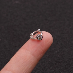 Tiny silver cartilage earring with sparkling zircon shown on a fingertip for size
