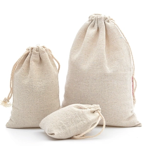 Trois sacs cadeaux en lin beige avec cordon de serrage montrant la texture du tissu naturel