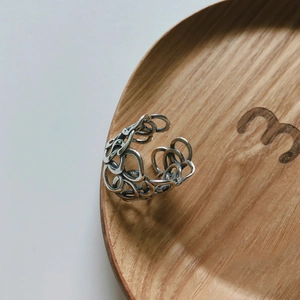 Detailed macro view of an oxidized 925 sterling silver woven ring on a wooden tray