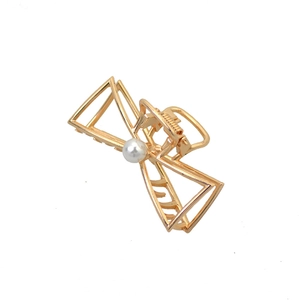 Detailed shot of golden alloy hair claw with pearl accent in geometric hollow design