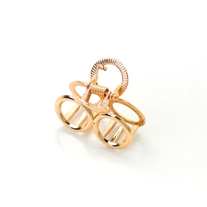 Close-up of a circular hollow gold metal hair claw clip with a polished finish