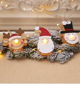Close-up of LED wooden Christmas ornaments featuring reindeer and Santa on snow