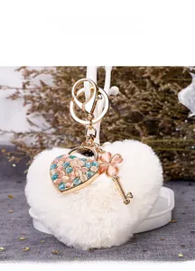Detail of white faux fur heart keychain with gold clasp and pink clover charms