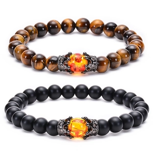 Detail of natural tiger eye and matte black beaded bracelets with crown metal accents