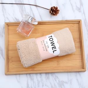 Close-up of rolled beige coral fleece towel with cloud label on a wooden tray
