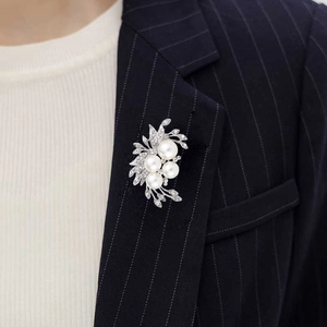 Close-up of elegant flower brooch with pearls and rhinestones on navy suit