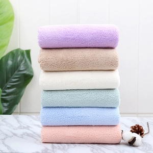 Close-up of thick coral fleece towels stacked in six colors on a marble surface