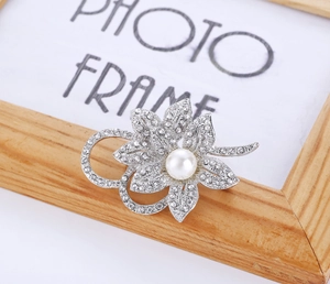 Detail of silver flower brooch with a central white pearl and sparkling rhinestones